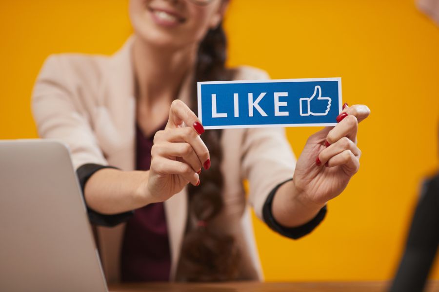 A woman holds up a blue sign that says "LIKE" with a thumbs-up icon. A woman holds up a blue sign that says "LIKE" with a thumbs-up icon.