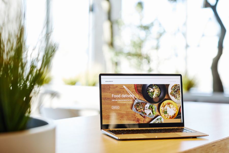 A laptop on a desk showing a food delivery website on its screen.