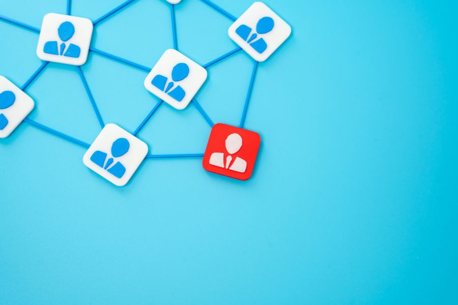 A network of person icons, with one red icon standing out from the blue ones, all connected by lines. A network of person icons, with one red icon standing out from the blue ones, all connected by lines.