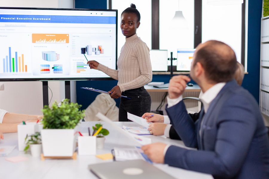 A woman gives a presentation with charts and graphs to her colleagues in a meeting room. A woman gives a presentation with charts and graphs to her colleagues in a meeting room.