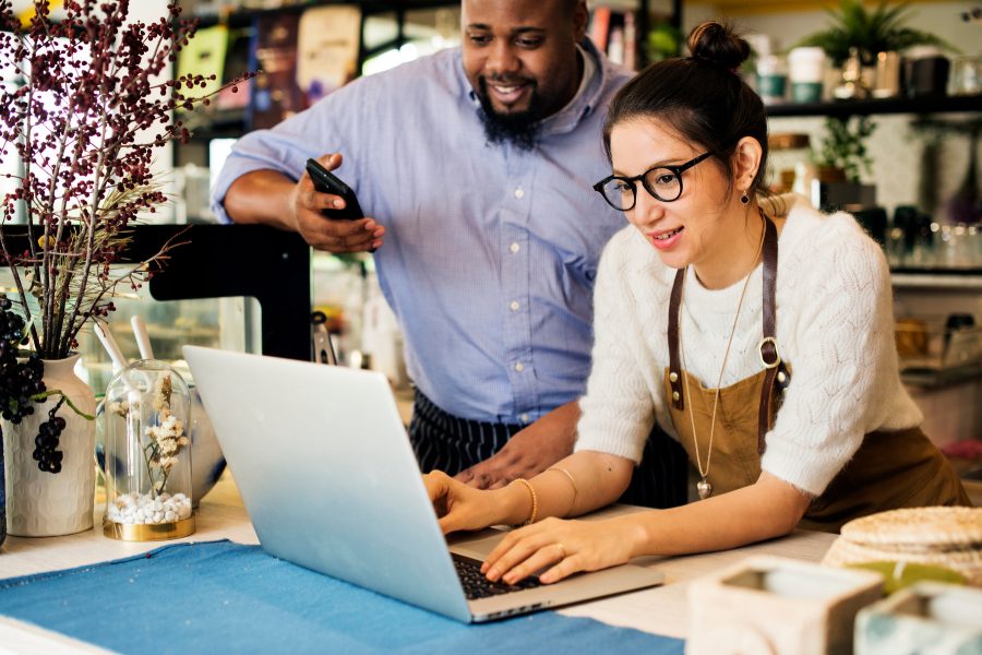 A man and woman collaborate on a laptop at a coffee shop, surrounded by warm lighting and cozy seating. A man and woman collaborate on a laptop at a coffee shop, surrounded by warm lighting and cozy seating.