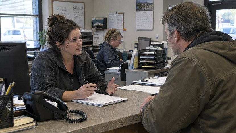 Office coordinator speaking with a customer while a desk phone sits nearby